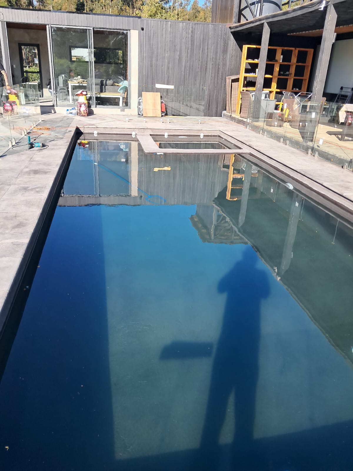 Piscina moderna oscura con reflejos e instalación de vidrios templados